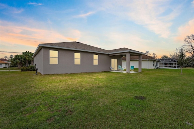 rear view of property with a patio area, a lawn, and stucco siding