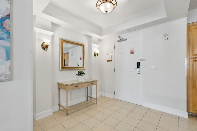 entryway with baseboards, a raised ceiling, crown molding, and light tile patterned flooring