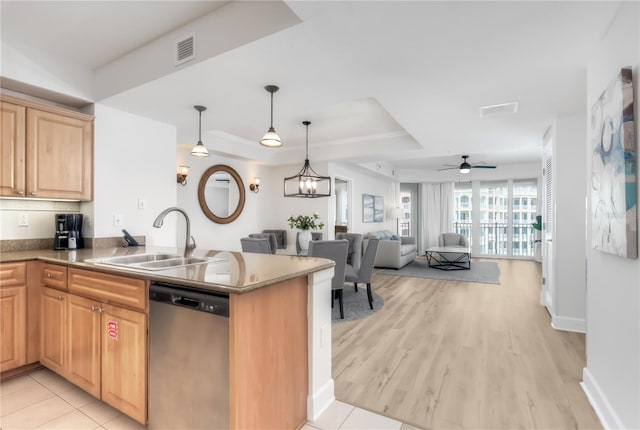 kitchen featuring decorative light fixtures, stainless steel dishwasher, open floor plan, a sink, and a peninsula