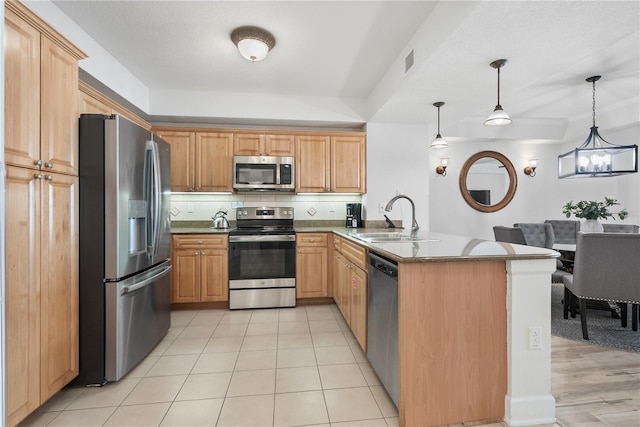 kitchen with stainless steel appliances, a peninsula, a sink, visible vents, and decorative backsplash