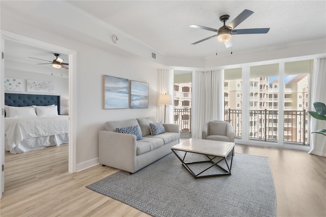 living area with a ceiling fan, crown molding, baseboards, and wood finished floors