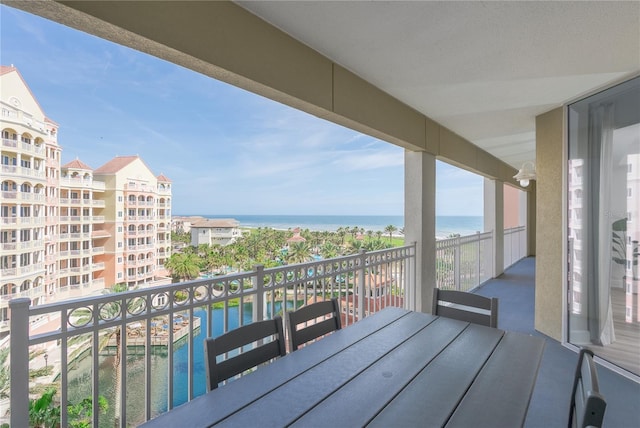 balcony featuring a water view and outdoor dining area