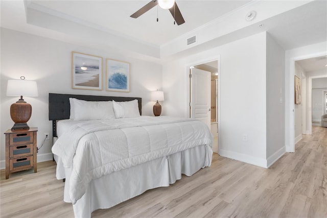 bedroom featuring light wood-style floors, baseboards, and a raised ceiling