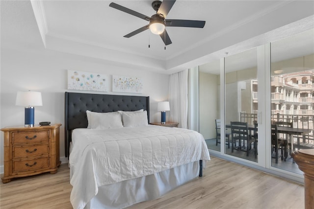 bedroom featuring ceiling fan, light wood-type flooring, a raised ceiling, and crown molding