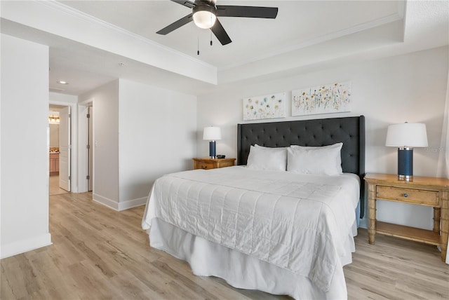 bedroom featuring ornamental molding, a tray ceiling, and light wood-style flooring