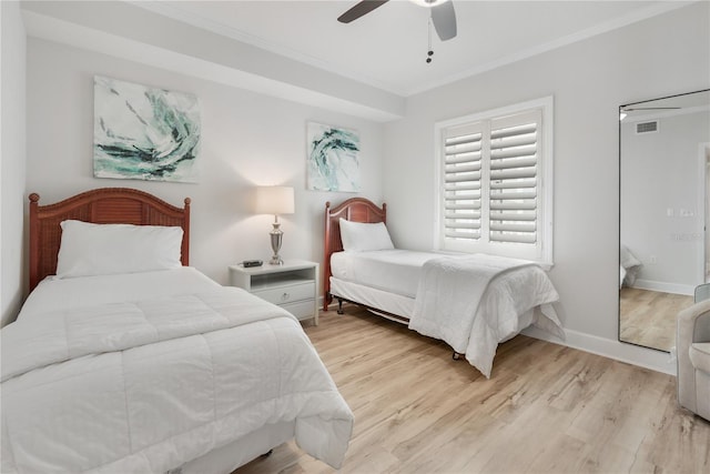 bedroom featuring baseboards, visible vents, a ceiling fan, crown molding, and light wood-style floors