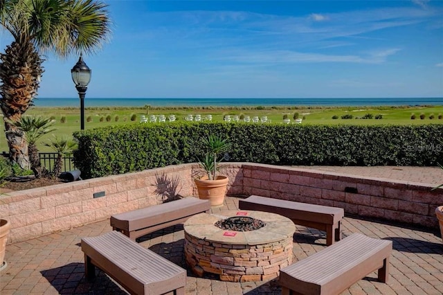 view of patio / terrace featuring a water view, fence, and a fire pit