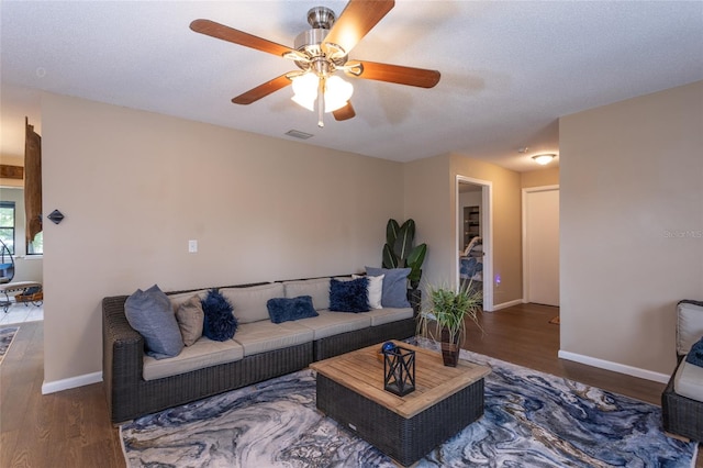 living room with a textured ceiling, wood finished floors, visible vents, and baseboards