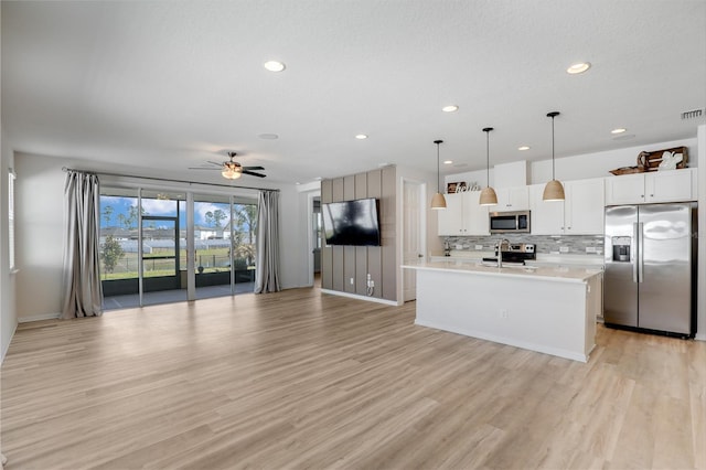 kitchen with tasteful backsplash, open floor plan, stainless steel appliances, light wood-style floors, and a sink