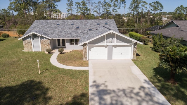 view of front of property featuring a shingled roof, concrete driveway, stone siding, an attached garage, and a front lawn