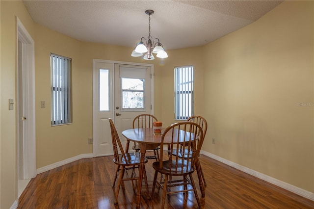 dining room with a textured ceiling, dark wood-style flooring, and baseboards