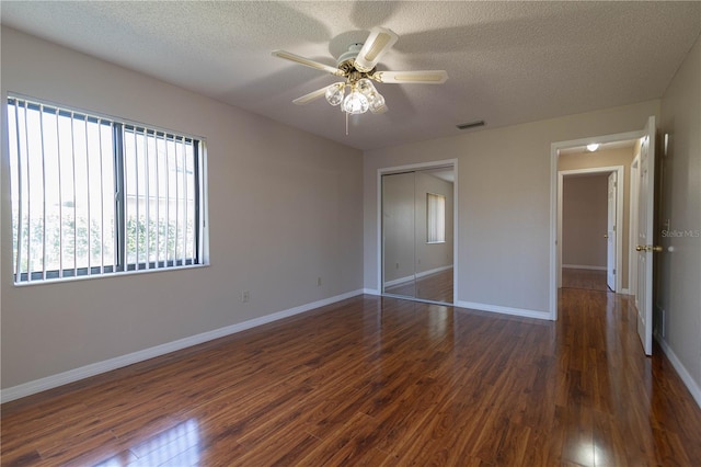 unfurnished bedroom featuring baseboards, visible vents, dark wood finished floors, a textured ceiling, and a closet