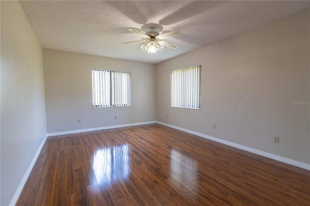 spare room with a textured ceiling, dark wood-type flooring, a ceiling fan, and baseboards