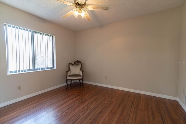 unfurnished room with dark wood finished floors, a textured ceiling, and baseboards