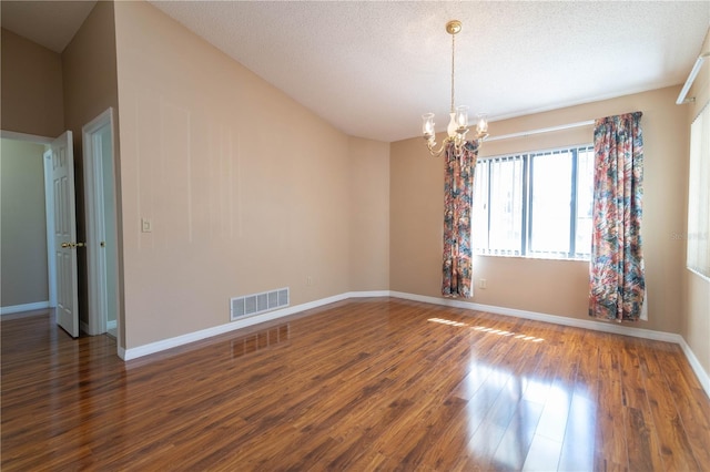 empty room with baseboards, visible vents, dark wood-type flooring, an inviting chandelier, and a textured ceiling