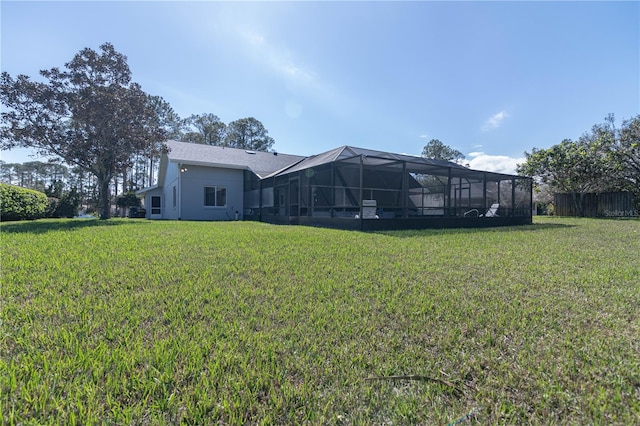 rear view of house with a lanai, a lawn, and stucco siding