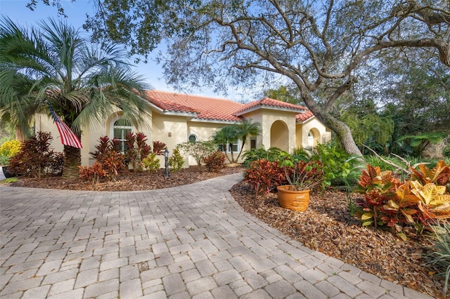 mediterranean / spanish house featuring a tile roof and stucco siding