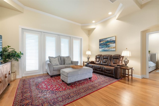 living room featuring a healthy amount of sunlight, light wood-style flooring, baseboards, and crown molding