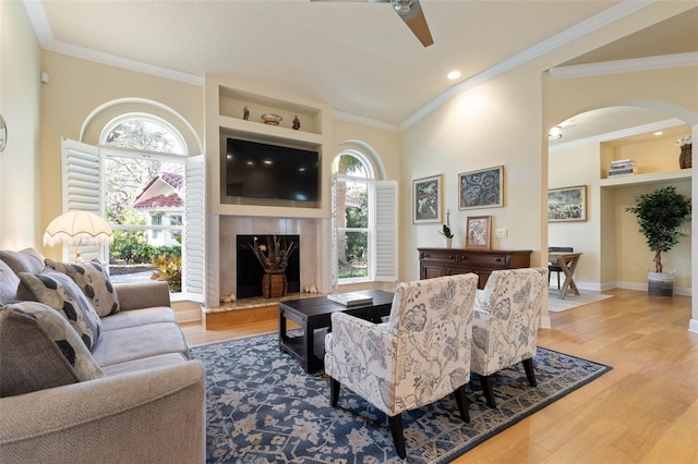 living area featuring ceiling fan, wood finished floors, a high end fireplace, and crown molding