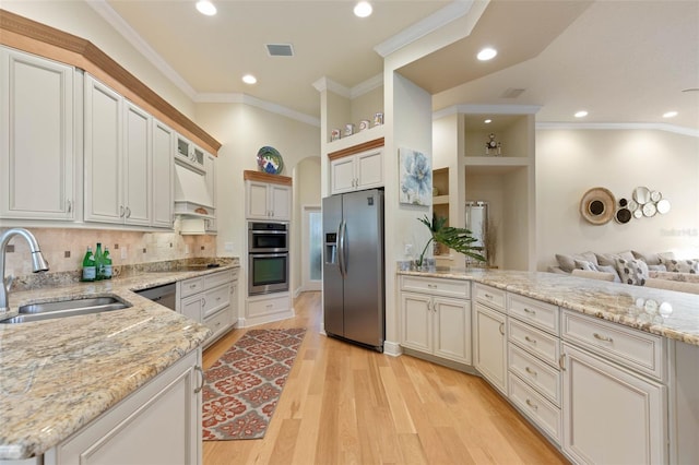 kitchen featuring a peninsula, stainless steel appliances, crown molding, light wood-style floors, and a sink