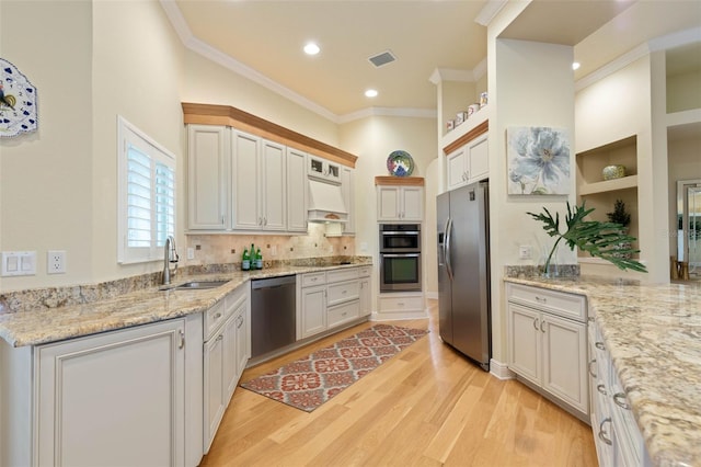 kitchen with visible vents, custom range hood, ornamental molding, stainless steel appliances, and a sink