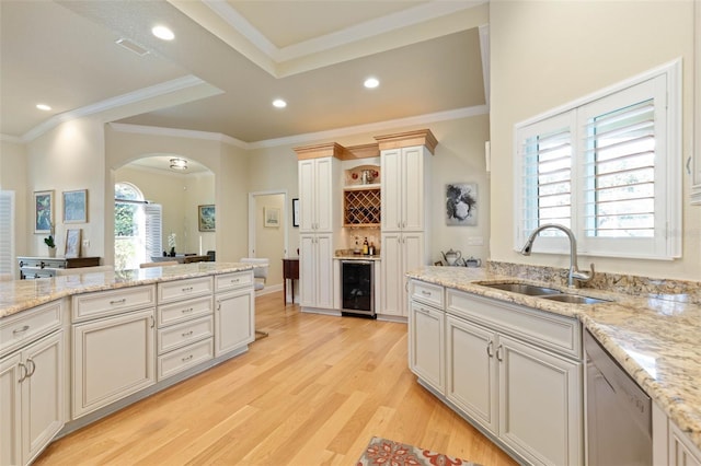 kitchen with arched walkways, dishwasher, light wood-style flooring, wine cooler, and a sink