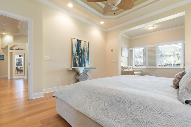 bedroom featuring recessed lighting, wood finished floors, baseboards, a raised ceiling, and crown molding