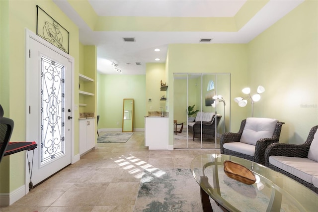 sitting room featuring a tray ceiling, visible vents, and baseboards