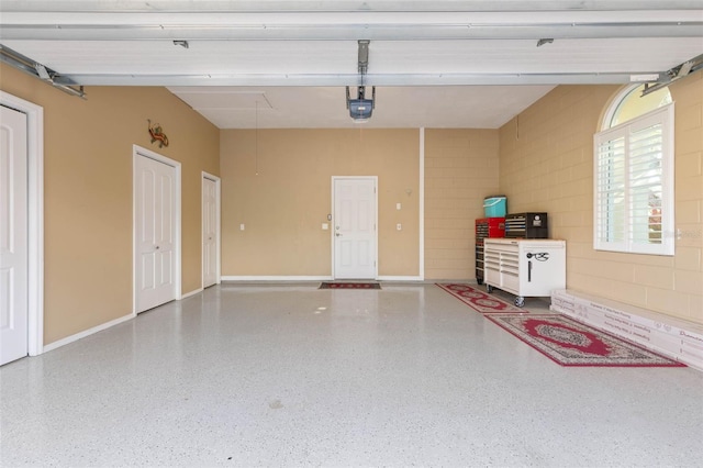 garage featuring baseboards, concrete block wall, and a garage door opener