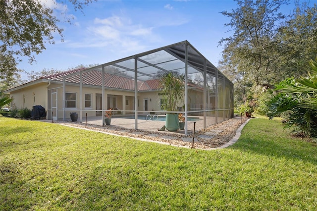 rear view of house featuring a patio, glass enclosure, a tiled roof, a lawn, and stucco siding