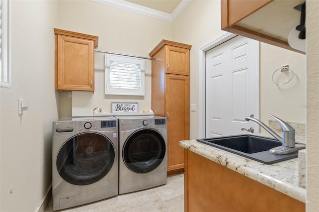 laundry room featuring cabinet space, baseboards, crown molding, washer and dryer, and a sink