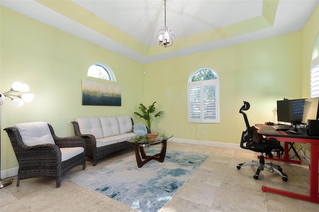 office area featuring a tray ceiling, baseboards, and an inviting chandelier