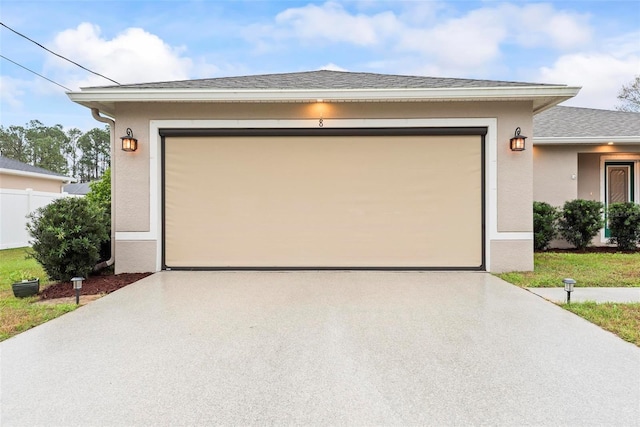 exterior space with a garage, driveway, a shingled roof, and stucco siding