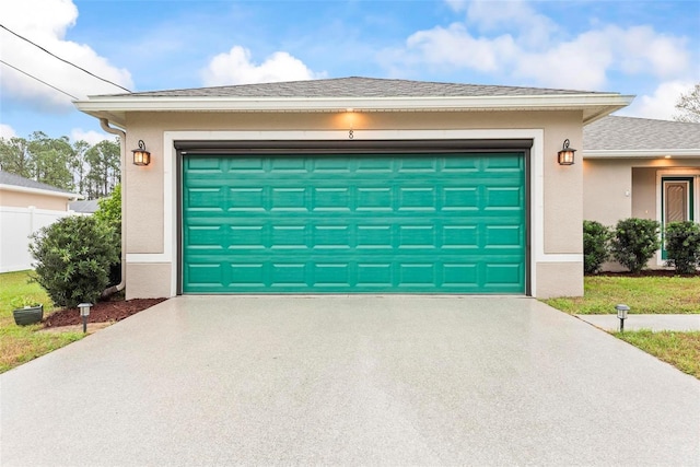 garage featuring driveway and fence