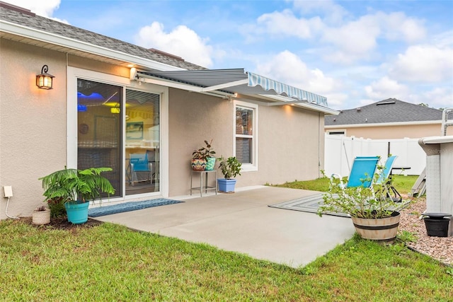 rear view of house featuring a lawn, a patio area, fence, and stucco siding