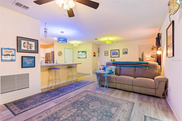 living room featuring light wood finished floors, visible vents, and baseboards