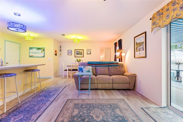 living area featuring light wood finished floors, visible vents, and baseboards