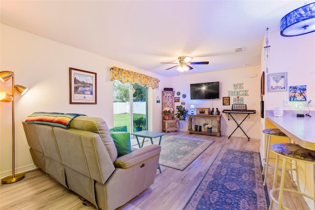 living room featuring ceiling fan, light wood finished floors, and baseboards