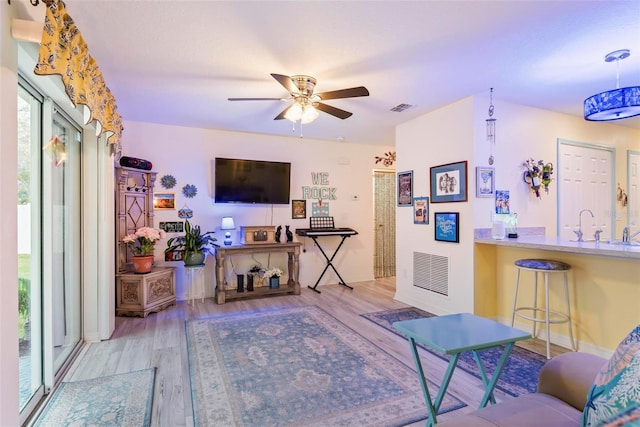 living room featuring ceiling fan, visible vents, and wood finished floors