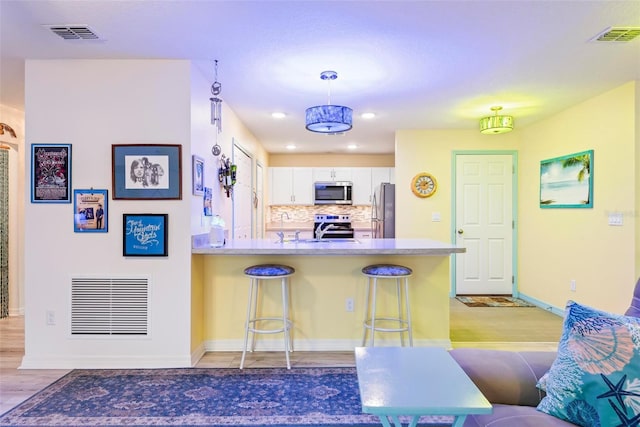 kitchen with stainless steel appliances, visible vents, a peninsula, and a kitchen breakfast bar