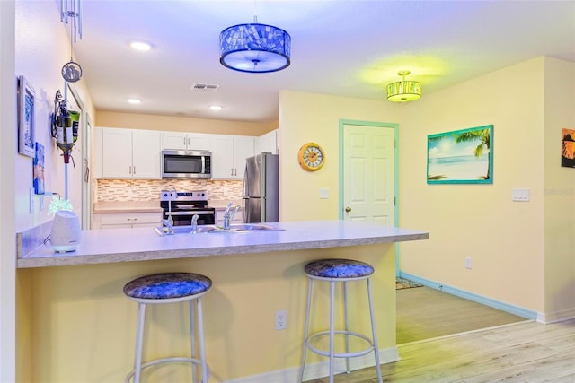 kitchen featuring a sink, white cabinetry, visible vents, appliances with stainless steel finishes, and tasteful backsplash