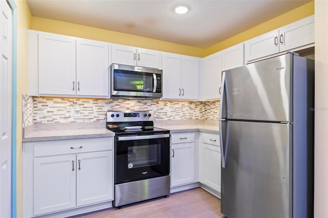 kitchen featuring appliances with stainless steel finishes, light countertops, and white cabinetry