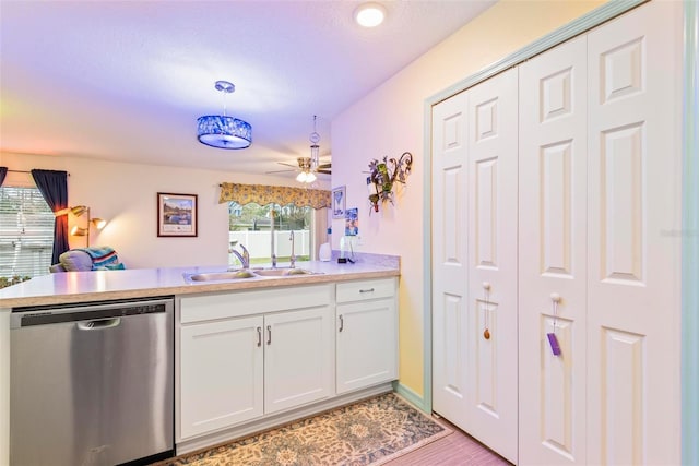 kitchen with pendant lighting, light countertops, white cabinetry, a sink, and dishwasher