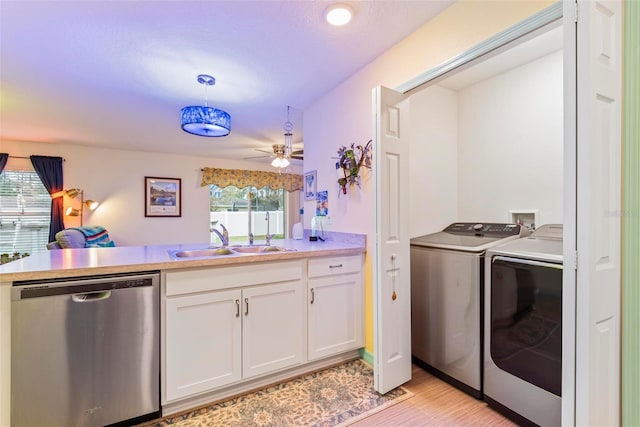 clothes washing area with laundry area, a ceiling fan, washer and dryer, light wood-type flooring, and a sink