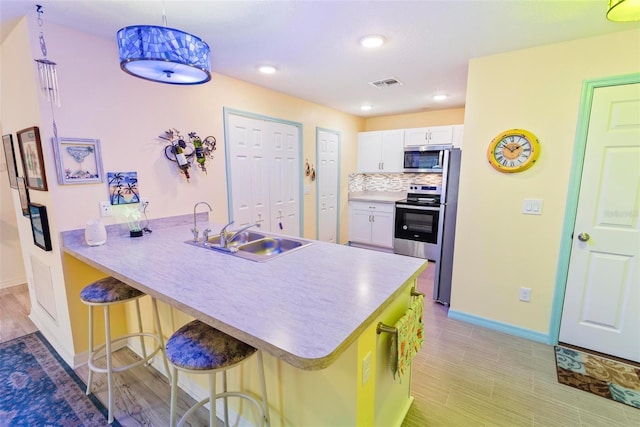 kitchen with stainless steel appliances, visible vents, decorative backsplash, a sink, and a kitchen breakfast bar