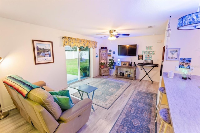 living room featuring visible vents, ceiling fan, light wood-style flooring, and baseboards