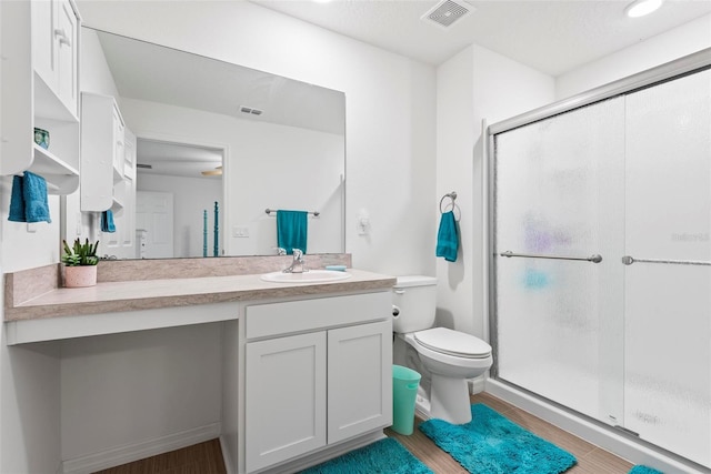 bathroom featuring a stall shower, visible vents, vanity, and toilet