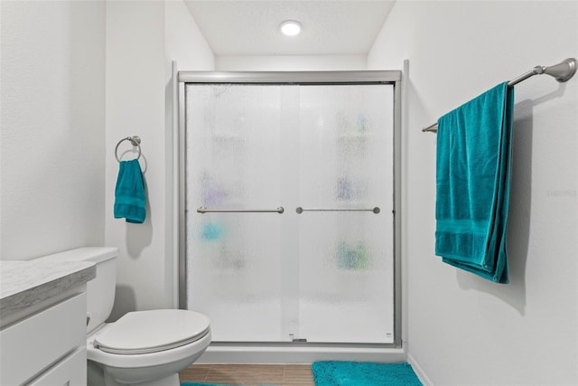 bathroom featuring toilet, a stall shower, and vanity