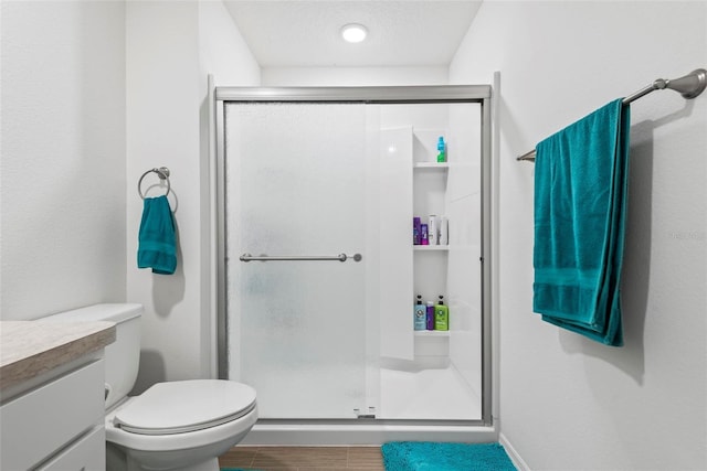 bathroom with a stall shower, vanity, and toilet