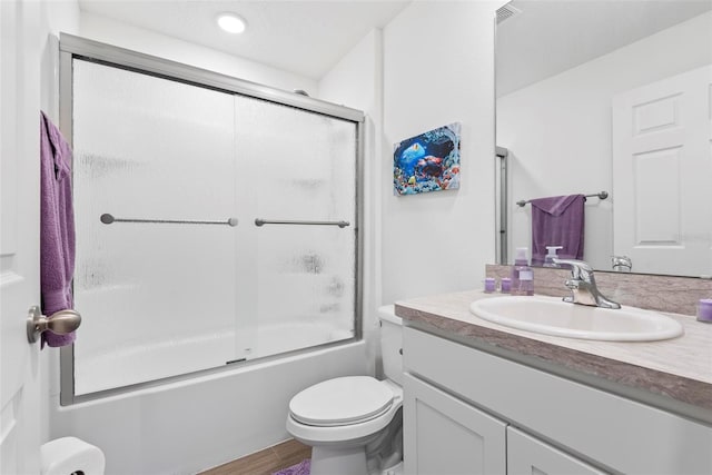 bathroom featuring toilet, shower / bath combination with glass door, wood finished floors, and vanity